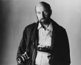 Ritratto di Gianni Berengo Gardin, fotografo con due macchine fotografiche al collo, sguardo intenso.