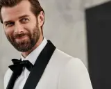 Elegancki mężczyzna w białej marynarce z czarnymi klapami i czarną muszką. Jego męski strój wieczorowy podkreśla jego urok.
