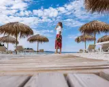 Kobieta na plaży, pod słomianymi parasolami, podziwia widok. To idealne miejsce na wyspie Rab, atrakcje czekają!