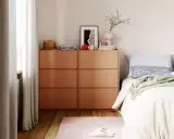 Ordnung im Schlafzimmer: Ein Nachttisch mit Schubladen, Bettwäsche und Dekoration.