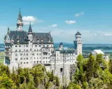 Märchenschloss Neuschwanstein, ein Meisterwerk romantischer Architektur, thront auf einem Felsen über einer malerischen Landschaft.