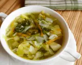Aromaticzny kapuśniak z młodej kapusty, pełen warzyw i ziół, podany w białej miseczce.
