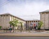 Warszawa: monumentalny budynek Muzeum Narodowego z flagami i drzewami przed wejściem.