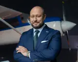 Biznesmen w garniturze na tle samolotu, gotowy do lotów Kraków-Lourdes.