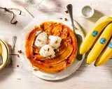 Tarte banane caramel beurre salé, garnie de boules de glace à la vanille et de noix de pécan. Des bananes Chiquita sont à côté.