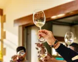 Manos brindando con copas de vino blanco. ¿Qué es chacolí? Es un vino joven y fresco, ideal para disfrutar en buena compañía.