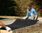 Preparando el terreno para saber como hacer hormigón para suelo. Colocando tela geotextil dentro de encofrado de madera.