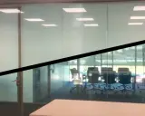 La lámina cristal inteligente cambia de opaca a transparente, mostrando una sala de reuniones.