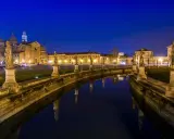 Prato della Valle di notte, un'idea di cosa vedere a Padova in un giorno. Statue e riflessi sull'acqua creano un'atmosfera magica.