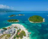 Widok na wyspy w Ksamilu, skąd widać prom na Korfu. Turkusowa woda, plaże i zielone wysepki.