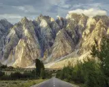 Droga w Karakorum Highway prowadzi przez surowe, skaliste góry oświetlone słońcem.