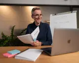 Lehrer erklärt **adjektive und adverbien englisch** mit einem Flipchart und Notizbuch.