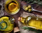 Aceite de oliva en botellas y cuenco, con aceitunas y romero. A pesar de sus beneficios, hay desventajas del aceite de oliva, como su precio.