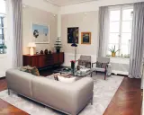 Ett modernt vardagsrum med en grå soffa, glasbord och konst. Johan Pråmell skulle trivas här.