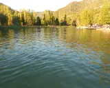 Gente disfrutando del agua en la playa de Cañamares, rodeada de árboles y montañas.