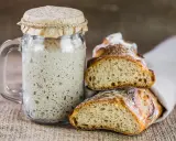 Un bocal de levain actif, prêt à être utilisé pour entretenir son levain, à côté de deux belles tranches de pain artisanal.