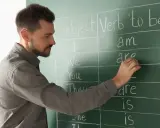 Nauczyciel pisze na tablicy "Subject", "Verb 'to be'". Przygotowanie do egzaminu z certyfikatem C1 angielski.