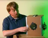 Mężczyzna prezentuje domową camera obscura z kartonu.