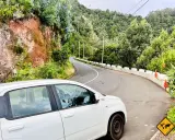 Weißes Auto auf einer kurvigen Straße auf Madeira. Die Fahrt durch die üppige grüne Landschaft ist ein Abenteuer.
