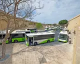 Kolejka zielono-białych autobusów Malta Public Transport czeka na pasażerów. Lotnisko na Malcie tętni życiem.