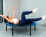 Frau macht ein intensives Workout auf einem Trampolin. Sie trainiert ihren Bauch, eine Übung, die man auch bei Tabata machen kann.