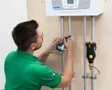 Instalator montuje separator zanieczyszczeń na rurze pod kotłem. Prawidłowe umiejscowienie zapewni ochronę systemu.