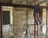 Trabajador realiza el empresillado de pilares en una obra. Se aprecian puntales metálicos y vigas de soporte.