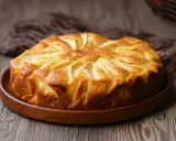 Una deliziosa torta di mele dorata, con le mele disposte a raggiera sulla superficie, pronta per essere gustata.