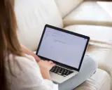 Kobieta pisze maila na laptopie, podkreślając ważne fragmenty tekstu.