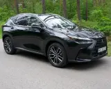 Lśniący czarny Lexus NX 2025 na tle zielonego lasu. Elegancki SUV gotowy na przygodę.
