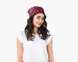 Uśmiechnięta dziewczyna z burzą loków, na głowie ma czerwoną bandana. Pokazujemy, jak zawiązać chustę na głowie.