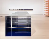 Installazione di Donald Judd con elementi blu e metallici su pavimento in legno chiaro, in una galleria d'arte.