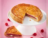 Galette framboise dorée sur un présentoir blanc, une part coupée révèle la garniture rose. Parfait pour une recette galette framboise.