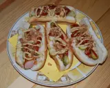 Cztery pyszne domowe hot dogi z kiełbaską, ogórkiem, ketchupem, musztardą i chrupiącą cebulką na talerzu.