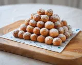 Montón de buñuelos caseros sencillos espolvoreados con azúcar glas sobre una tabla de madera.