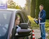 Młoda kobieta w okularach uczy się jeździć, a instruktor pokazuje jej, ile ważny jest kurs prawa jazdy.