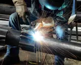Un saldatore crea un legame forte, il vero significato del welding. Scintille luminose illuminano il metallo.