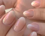 Delikatne, owalne paznokcie z subtelnym, perłowym połyskiem. Klasyczny francuski manicure w nowoczesnym wydaniu, podkreślający naturalne piękno dłoni.