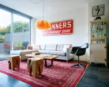 En röd persisk matta ger inspiration till detta vardagsrum med grå soffa, träpallar och en vintage-skylt.