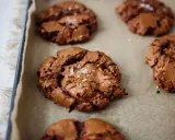 Saftige schoko cookies mit Meersalzflocken auf Backpapier, bereit zum Genießen.