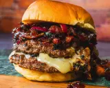 Saftiger Burger mit doppeltem Patty, geschmolzenem Käse und einer süß-salzigen Bacon Jam-Schicht, garniert mit roten Zwiebeln.