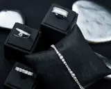 Gioielli scintillanti, anelli e bracciali con diamanti, esposti su supporti neri e pietre levigate.