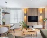 Przytulny salon w domu z drewnianą ścianą RTV, jadalnią i wygodną kanapą.