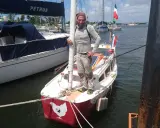 Yann Quenet, prêt pour l'aventure avec son baluchon, pose sur son voilier orné d'une poule.