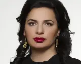 Portret Ruja Ignatova, kobiety o ciemnych włosach i wyrazistych ustach, w złotych kolczykach.