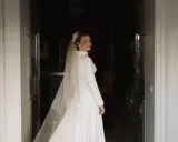 Novia sonriente con velo y vestido blanco, parte de un ajuar de novia tradicional, lista para su gran día.