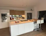 Cuisine moderne et lumineuse, avec îlot central. On y voit la différence entre une cuisine aménagée (meubles) et équipée (électroménager).