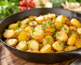 Poêlée de pommes de terre sautées, dorées et parsemées de persil frais, dans une poêle en fonte. Un délice simple et savoureux.
