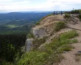 Widok z Sokolic w Beskidzie Żywieckim. Stroma ściana skalna opada w dolinę pełną zielonych lasów.