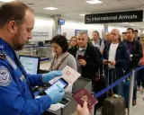 Funkcjonariusz służby celnej sprawdza paszporty w kolejce do odprawy na lotnisku.